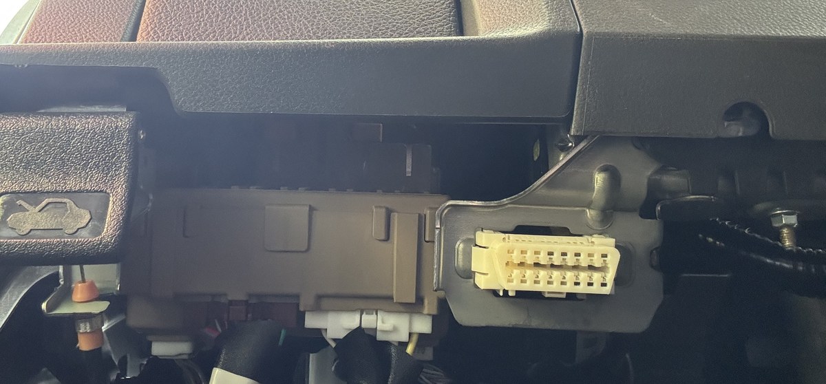 Empty OBD2 port under the dash next to the hood release lever
