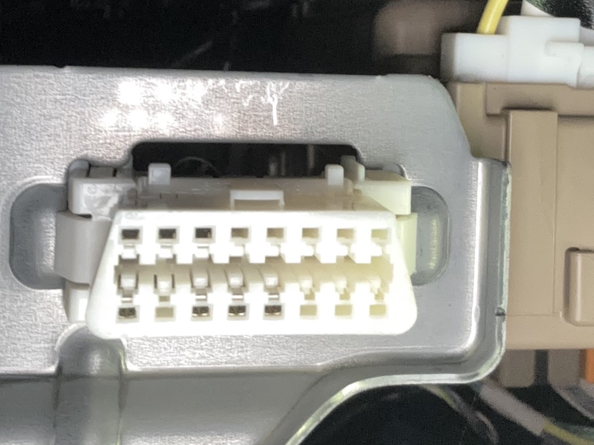 Empty OBD2 port showing trapezoid shape with wide edge toward the floor